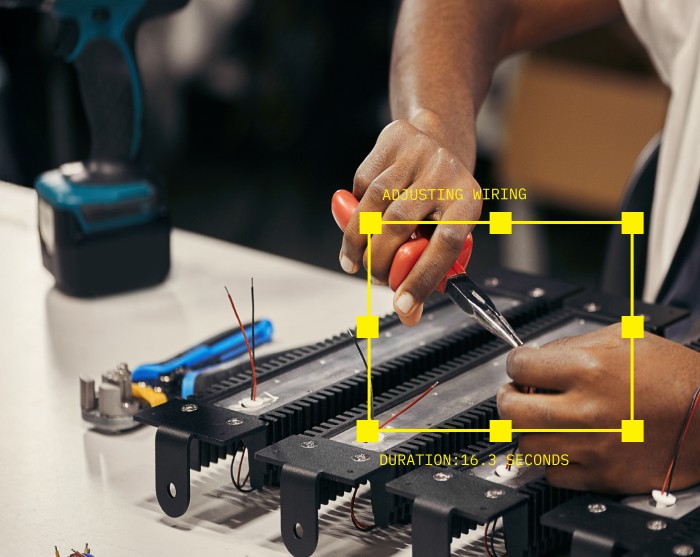 Hands adjusting wiring on an assembly with pliers