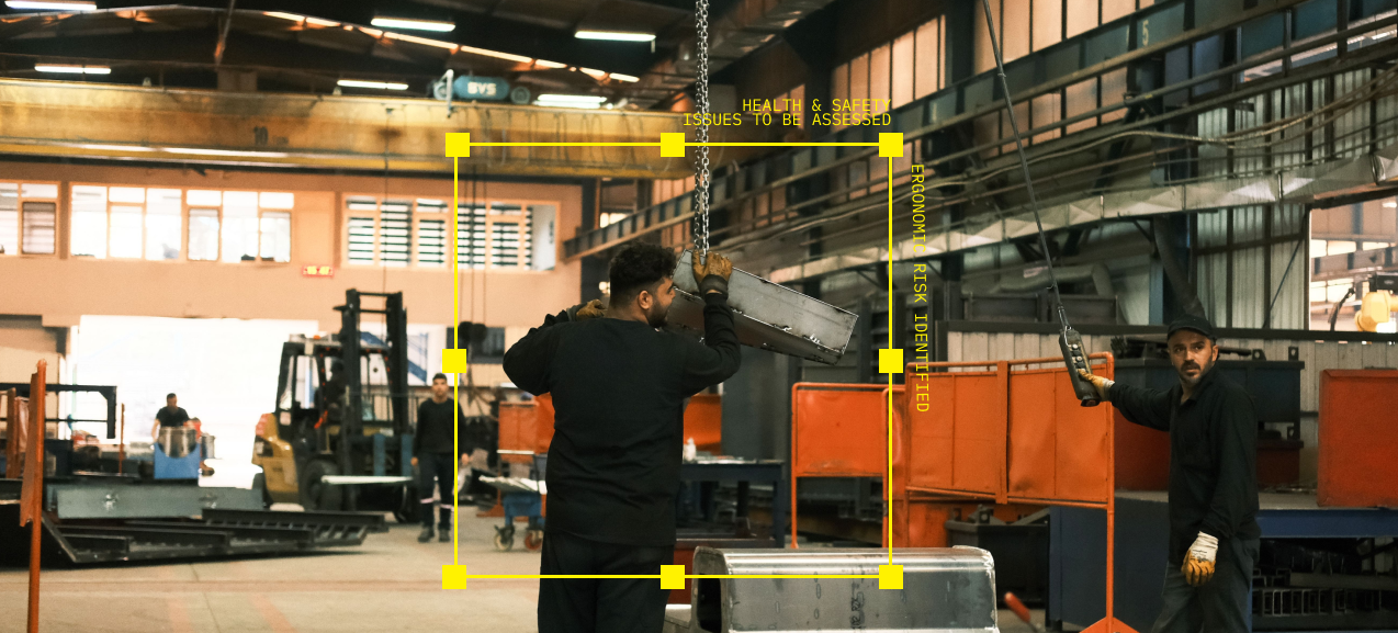 Workers guiding a crane-lifted steel part in a fabrication shop